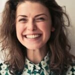 Portrait of a joyful brunette woman with a vibrant smile indoors, capturing happiness and positivity.