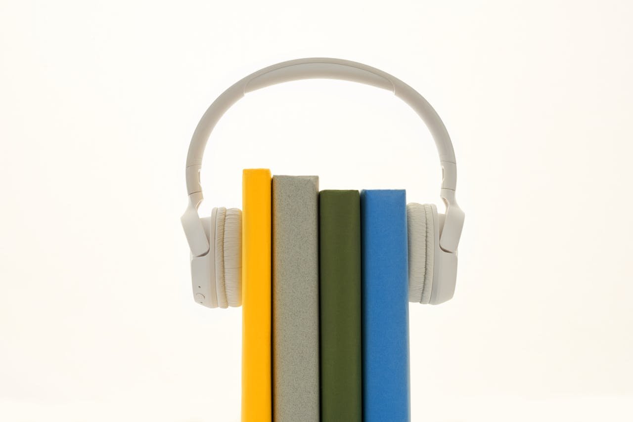 White headphones resting on colorful books, symbolizing modern audio technology.
