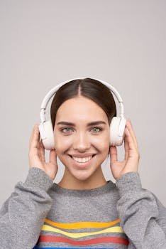 Portrait of a smiling woman wearing headphones and enjoying music indoors.