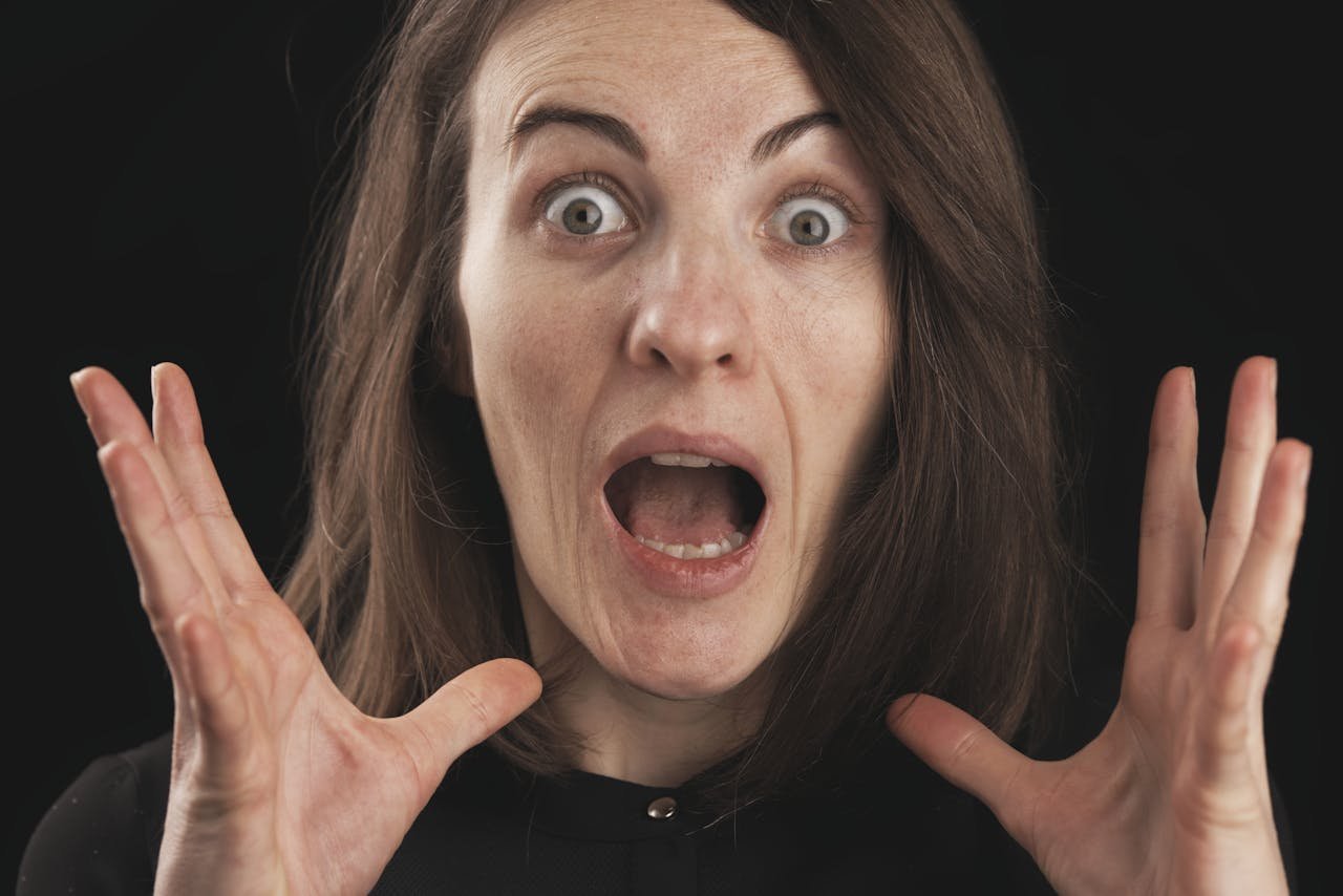 Close-up of a woman expressing shock and surprise with wide eyes and open mouth.